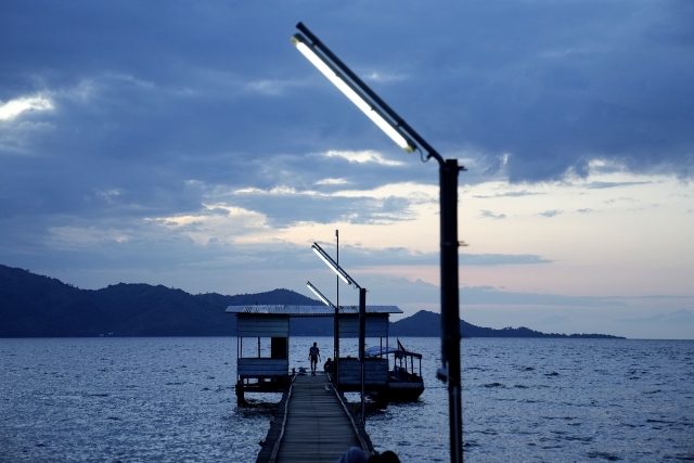 A man walks on a pier on Karampuang Island whose electricity relies on solar power plants, in West Sulawesi, Indonesia
